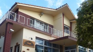 A two-story building with a balcony, a sign indicating it is a mining association, and a staircase leading to the entrance. - Colonia Aoma Villa Carlos Paz (Villa Carlos Paz)