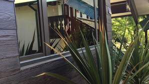 Un edificio moderno con una terraza de madera y una planta en maceta al frente.