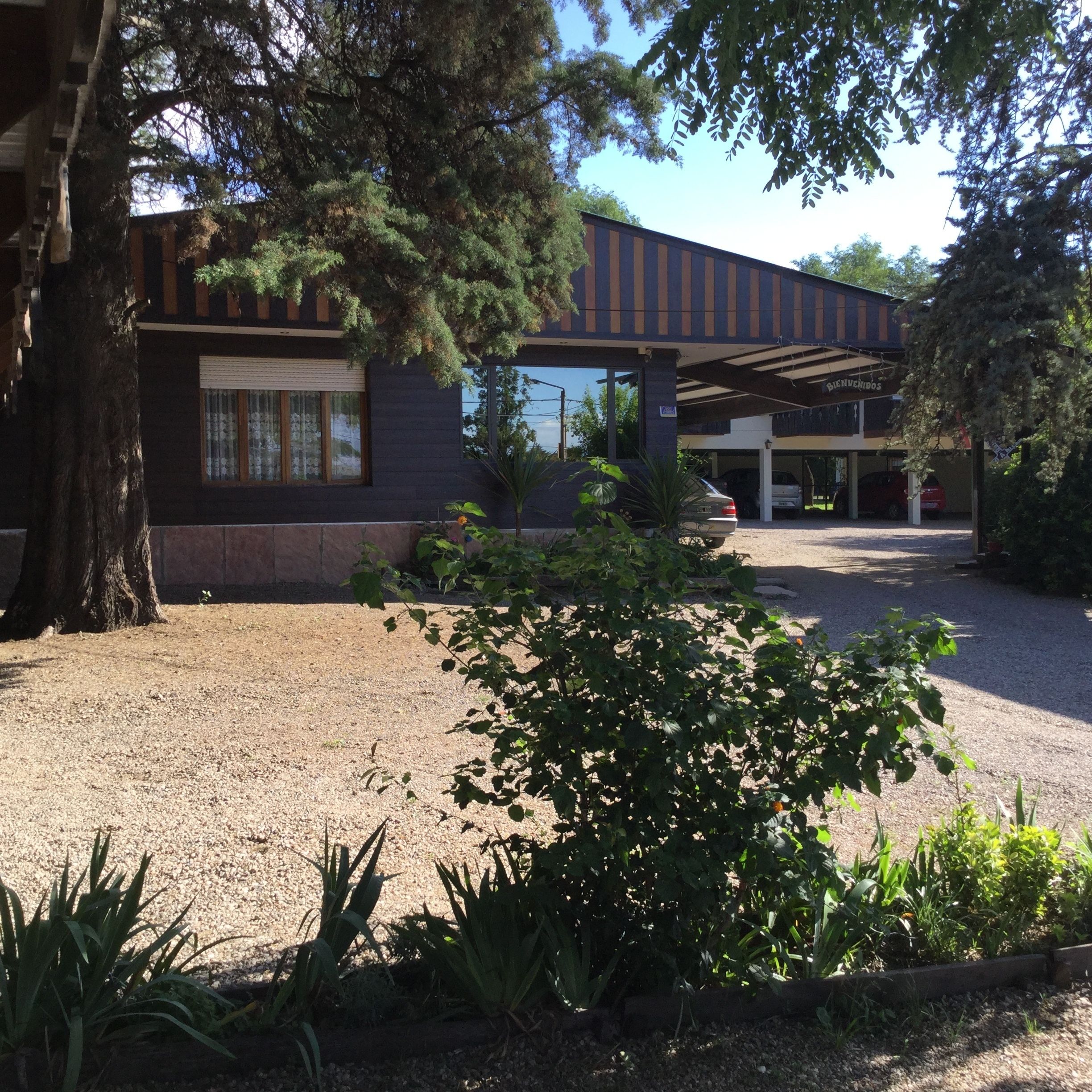 A building with a dark facade, a covered parking area, and a gravel driveway.
