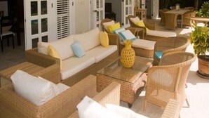 A sunlit outdoor seating area with wicker furniture, including sofas and chairs, and a glass coffee table. - Villa Maravilla (Punta Cana)