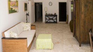 A room with a sofa, a small table, a lamp, and a wooden cabinet. - Villa Maravilla (Punta Cana)