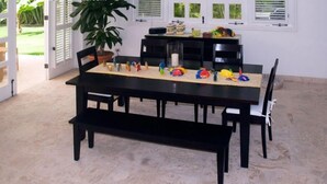 A dining table with black chairs, a bench, and colorful toys on the table. - Villa Maravilla (Punta Cana)