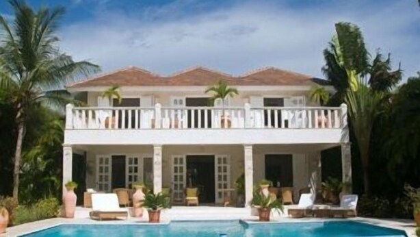 A two-story house with a swimming pool, surrounded by palm trees and a clear sky. - Villa Maravilla (Punta Cana)
