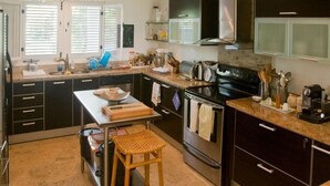 A kitchen with a central island, stainless steel appliances, and a variety of utensils and appliances on the countertops. - Villa Maravilla (Punta Cana)