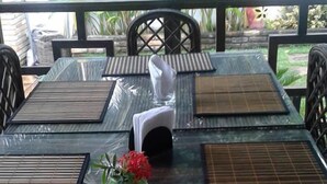 Une table à manger avec des chaises noires et un vase rempli de fleurs rouges.