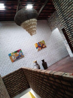 Une pièce avec un mur en briques, un luminaire suspendu et deux œuvres d’art.