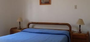 En säng för en person med en sänggavel i trä och två sängbord, var och en med en lampa.