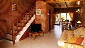 A cozy living room with a wooden staircase, a television, and a sofa. - Cabañas Madre Tierra (Valeria del Mar)