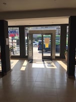 Entrada de hotel con puerta giratoria, piso de baldosas y vista de la calle.