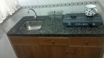 Cocina con encimera de granito, pileta de acero inoxidable y cafetera.