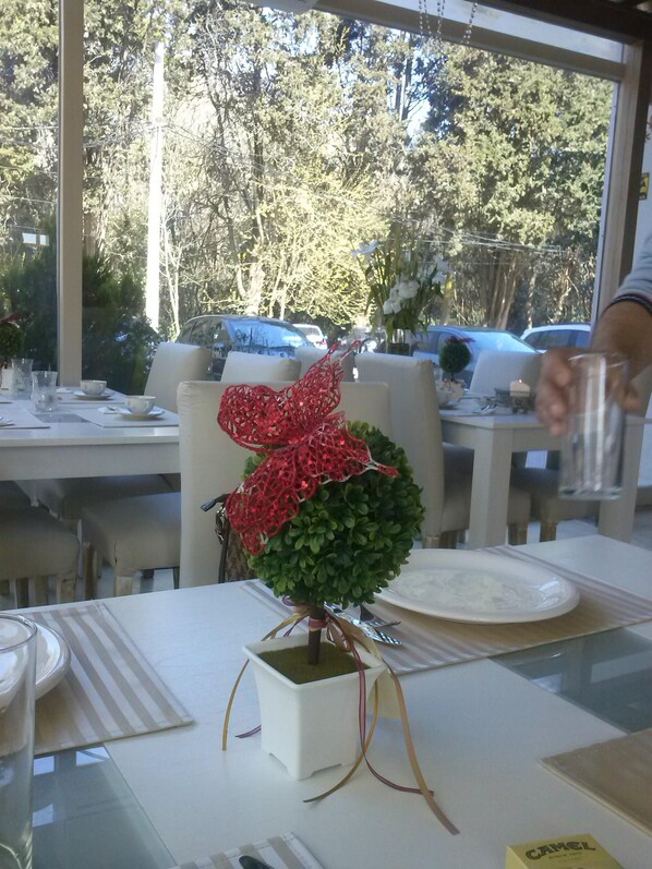 A dining table with a centerpiece of a red and green plant, white plates, and clear glasses. - Suites del Pilar (La Lonja)