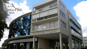 Un edificio moderno con una facciata curva e numerosi balconi. Il nome "CONCORD PILAR" è ben visibile sulla struttura.