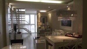 Un interno moderno con una scala, zona pranzo e un lampadario.