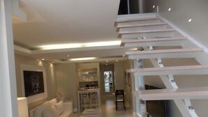 Un interno moderno con una scala, una zona living con divano e un'area pranzo.