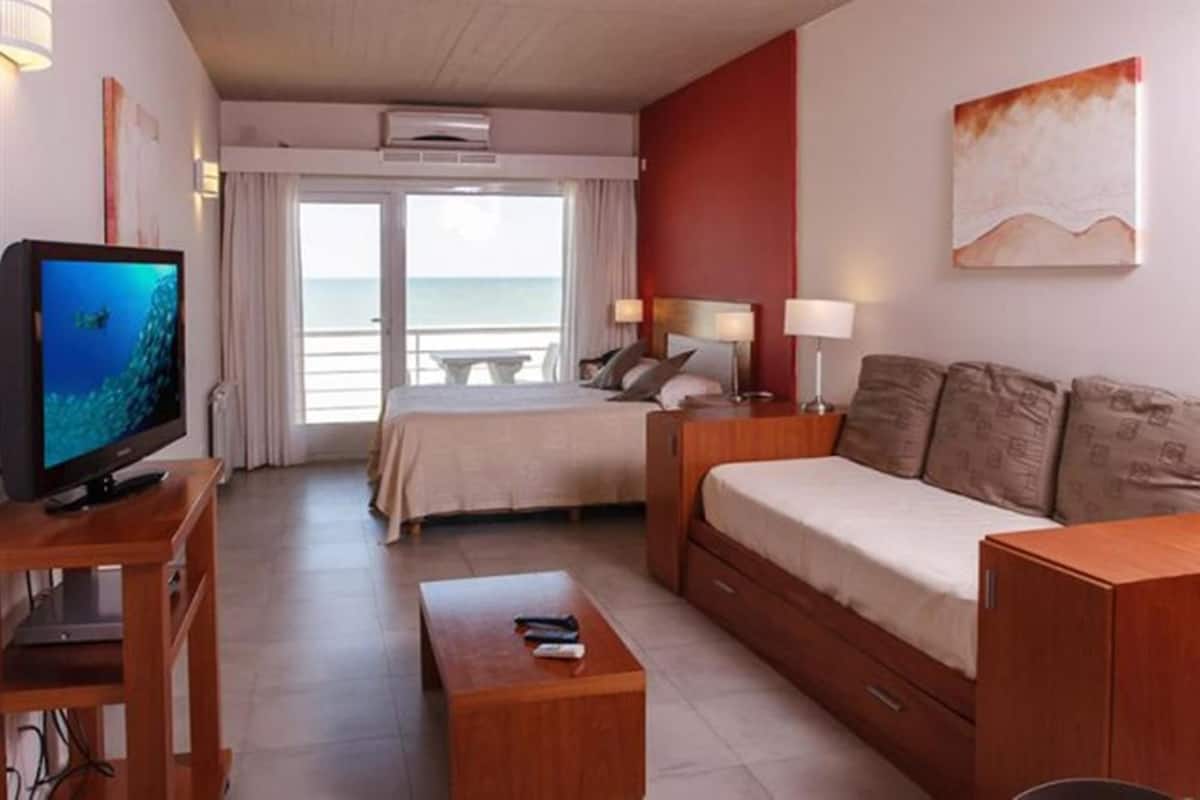 A hotel room with a bed, a sofa, a TV, and a table.