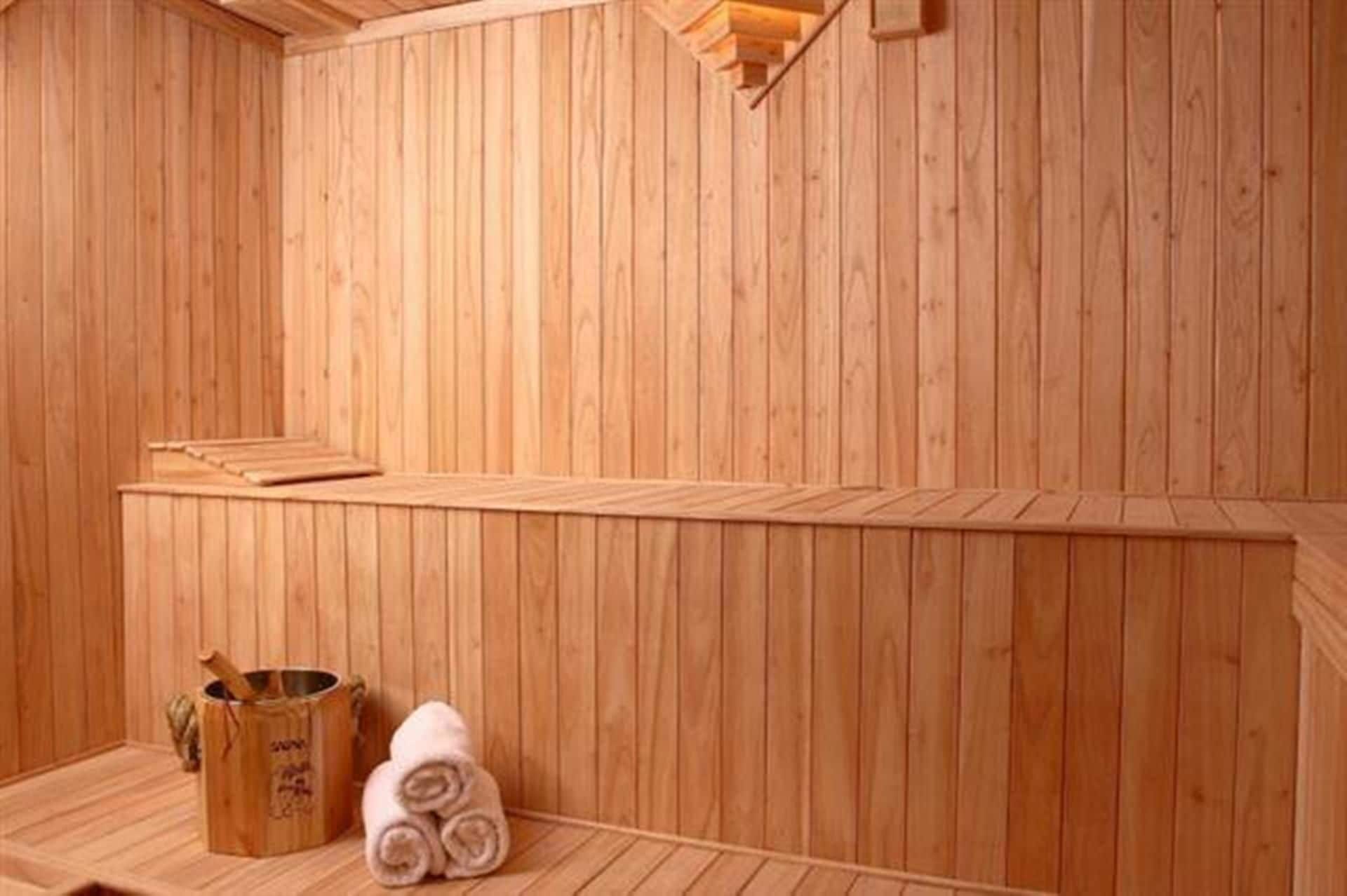 A wooden sauna with benches, a bucket, and towels.