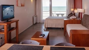 A hotel room with a bed, a sofa, a TV, and a view of the sea. - Parada 47 Apart de Playa (Villa Gesell)