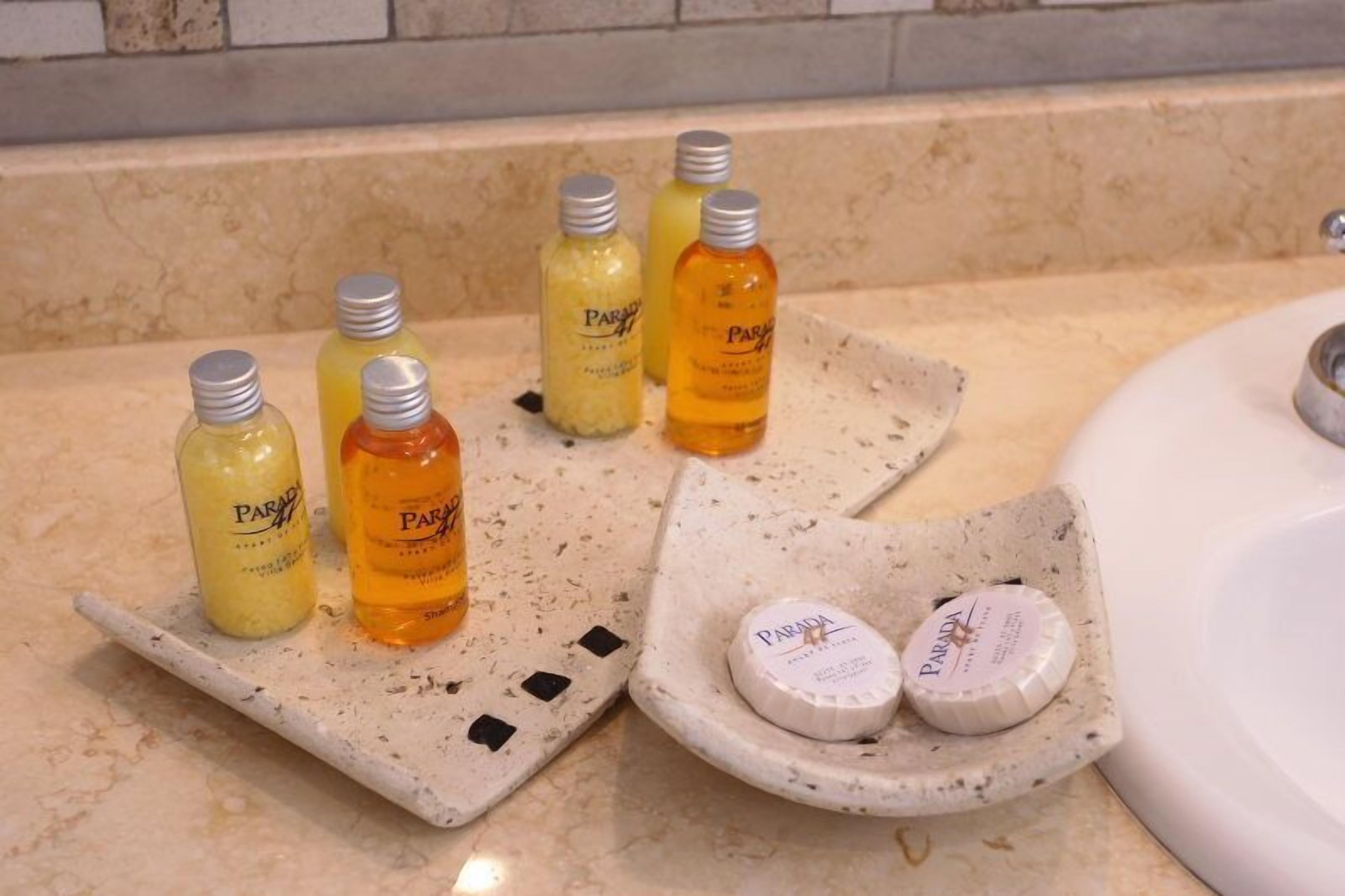 Una encimera de baño con diversos artículos de aseo, incluyendo botellas y jabones.