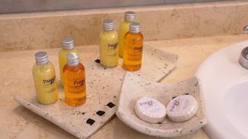 Una encimera de baño con diversos artículos de aseo, incluyendo botellas y jabones.
