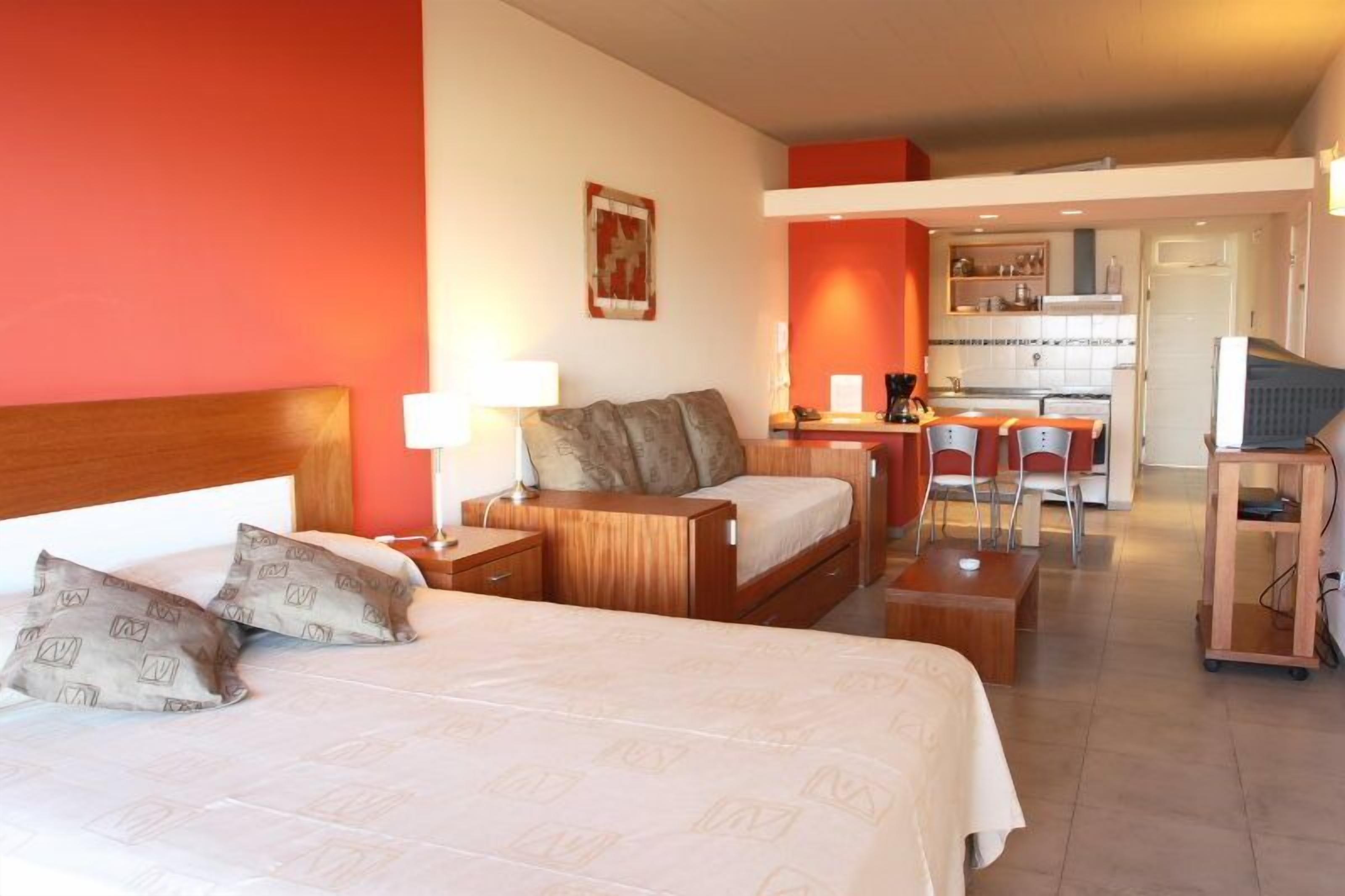 Una habitación de hotel con cama, escritorio, silla y kitchenette.