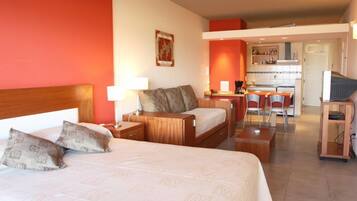 Una habitación de hotel con cama, escritorio, silla y kitchenette.