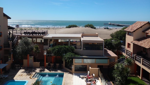 A resort with a swimming pool, beach view, and a pier in the background. - Complejo Playa Norte (Mar de Ajo)