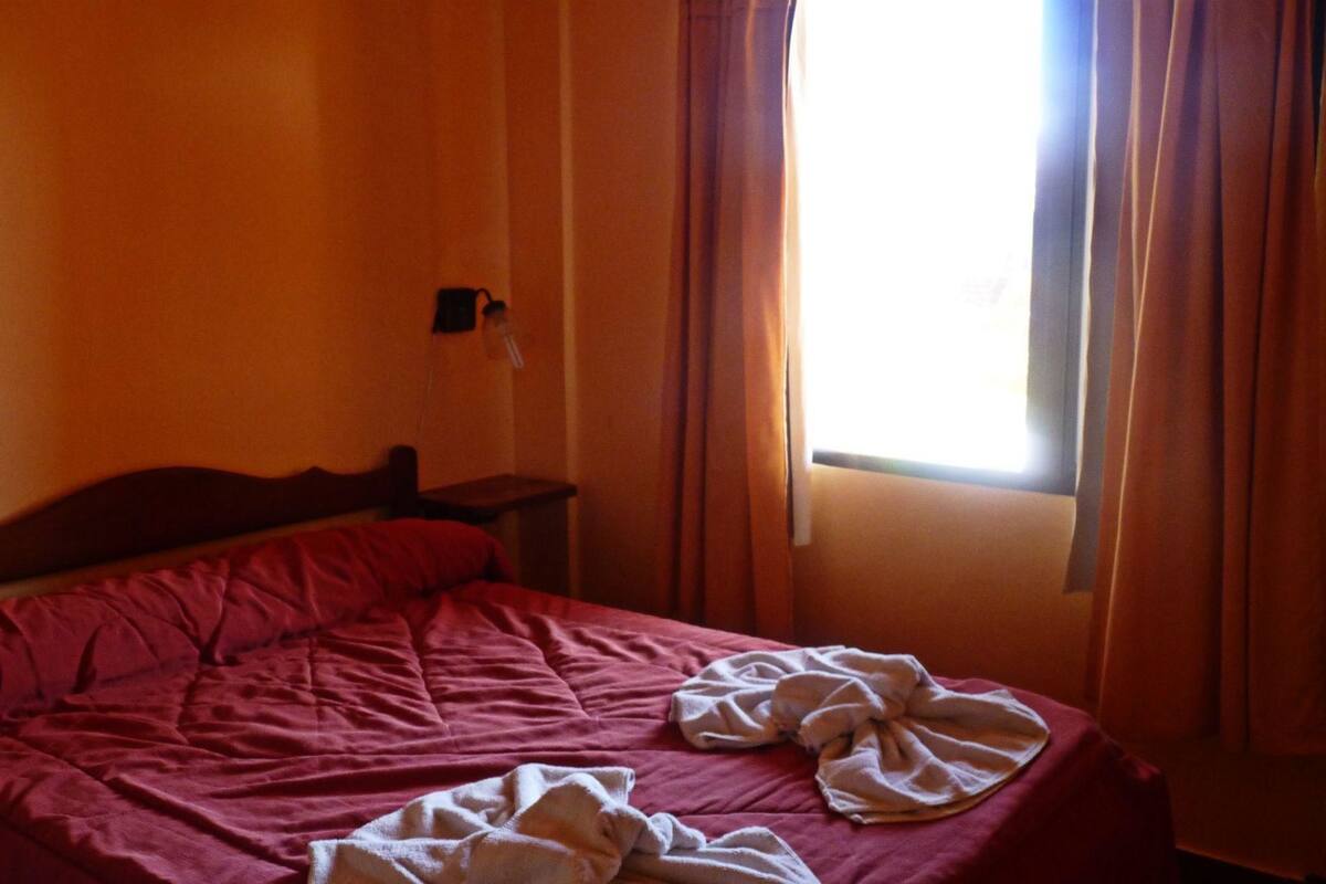 A room with a bed, a nightstand, and a window with curtains.