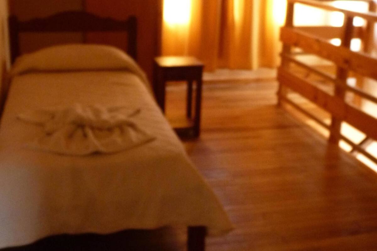 A room with a bed, a small table, and a wooden bench.