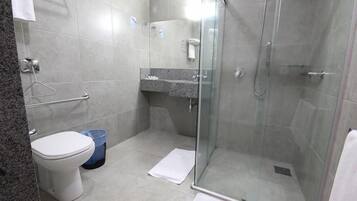A modern bathroom with a glass shower enclosure, a toilet, and a sink with a countertop.