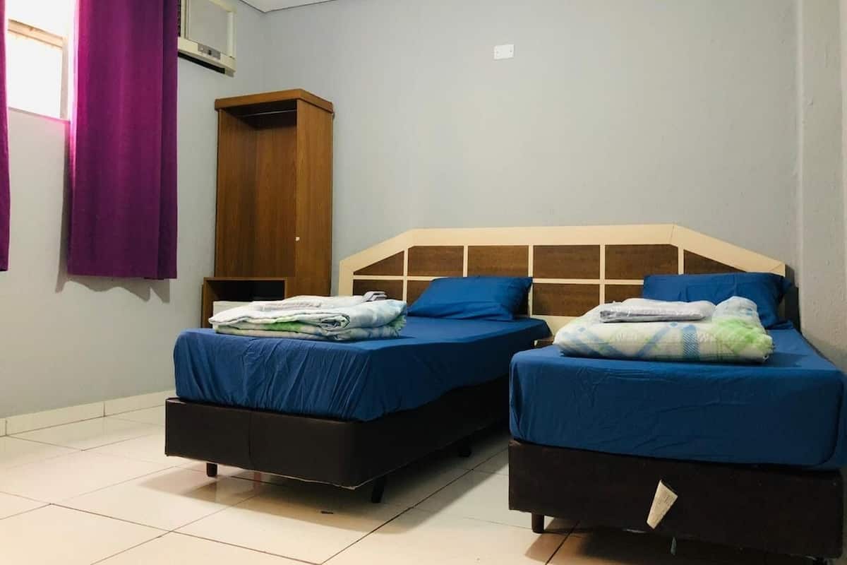 Une chambre avec deux lits, une armoire en bois et des rideaux violets.