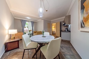 A dining area with a round table, four chairs, a lamp, and a painting on the wall. - Suites Newton (Mexico City)