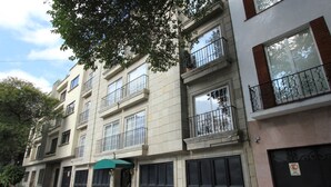 A multi-story residential building with balconies, large windows, and a green awning over the entrance. - Suites Newton (Mexico City)