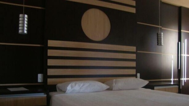 Una habitación de hotel moderna con una cama grande, cabecero de madera y una decoración circular en la pared.