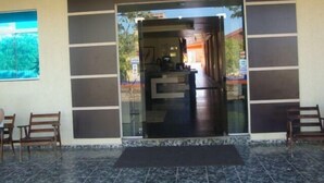 Entrada de un hotel con un mostrador de recepción y una puerta de cristal.