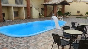 Una piscina con solárium de azulejos, rodeada de mobiliario exterior y una escalera que conduce a un nivel superior.