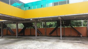 Un parking à plusieurs niveaux avec des murs jaunes et orange, de nombreux escaliers et un sol en béton.