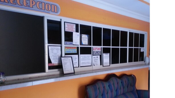Un espace d’accueil avec une enseigne indiquant « RÉCEPTION » et plusieurs affiches sur les vitres.