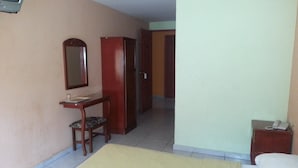 Une chambre d’hôtel comprenant un lit, un bureau avec une chaise, une armoire, un miroir et un téléphone.
