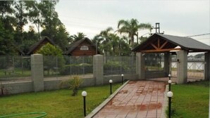 Un camino pavimentado que conduce a una entrada con puerta y un pequeño pabellón.