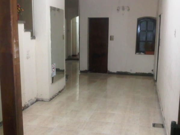 A hallway with a tiled floor, a door at the end, and a window on the right wall.