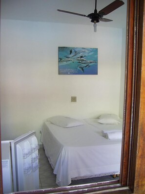 Un dormitorio con una cama, un ventilador de techo, una lámpara de pared y un cartel.
