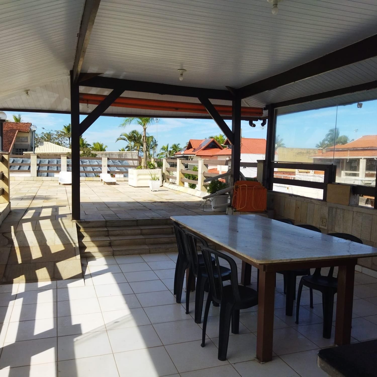 An outdoor patio area with a table and chairs, a covered seating area, and a view of buildings in the background.