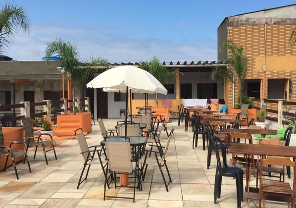 An outdoor patio with tables and chairs, some with umbrellas, and a building in the background.