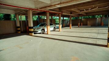 Un estacionamiento vacío con pilares de hormigón y un coche blanco dentro.