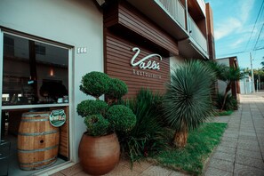 A restaurant with a wooden facade, a balcony, and potted plants.