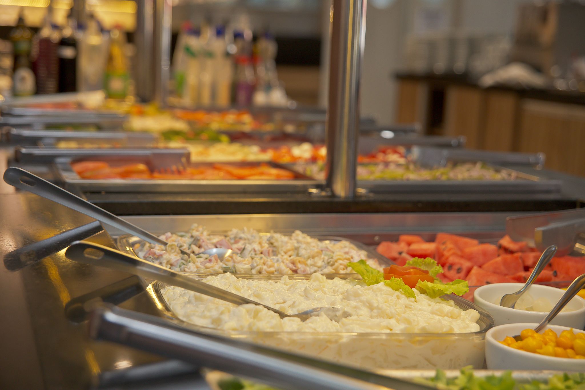 A buffet with various food options including salads, fruits, and other dishes.