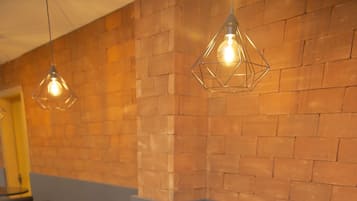 Un interior de restaurante con mesas redondas, sillas de cuero negro, paredes de ladrillo y lámparas colgantes.