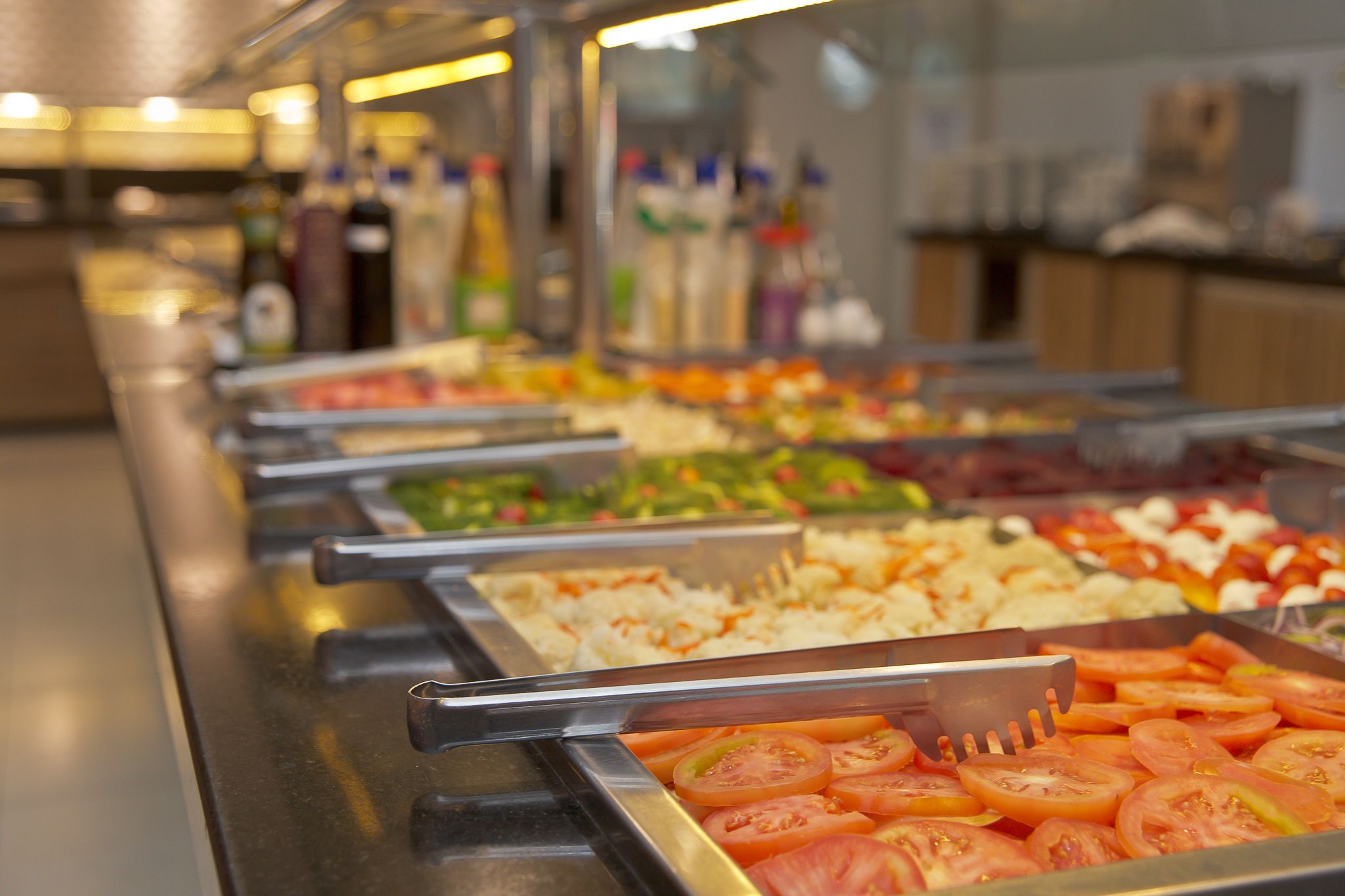 Un bufé con diversos alimentos, incluyendo tomates en rodajas, ensaladas y otros platos preparados.