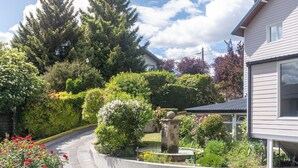 Ein Wohngebiet mit einem Haus, einem Garten mit verschiedenen Pflanzen und Blumen sowie einer Steinfontäne.