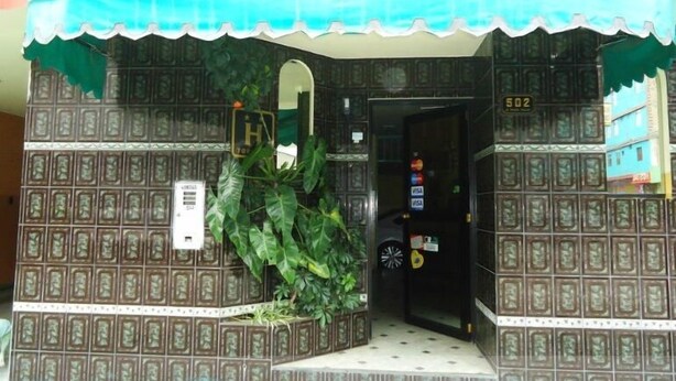 Facciata di un edificio con decorazioni esterne, una porta con la scritta '502' e una piccola pianta di fronte.